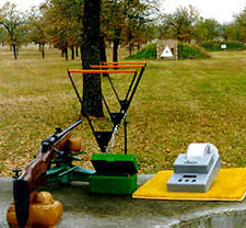 Outdoor field with a series of triangular frames in line with a target, past a rifle and measuring devices.