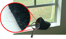 Imagen de una gorra tejida en el alfizar de una ventana, con acercamiento que muestra pelos