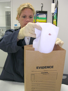 Image of woman properly handling biological evidence into a brown paper bag.